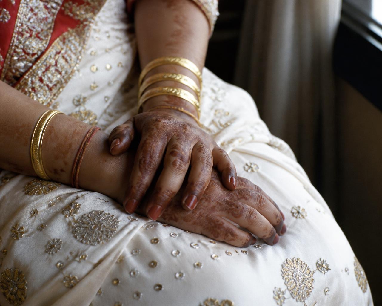 Candid close-up of bridal hands with mehendi and gold bangles